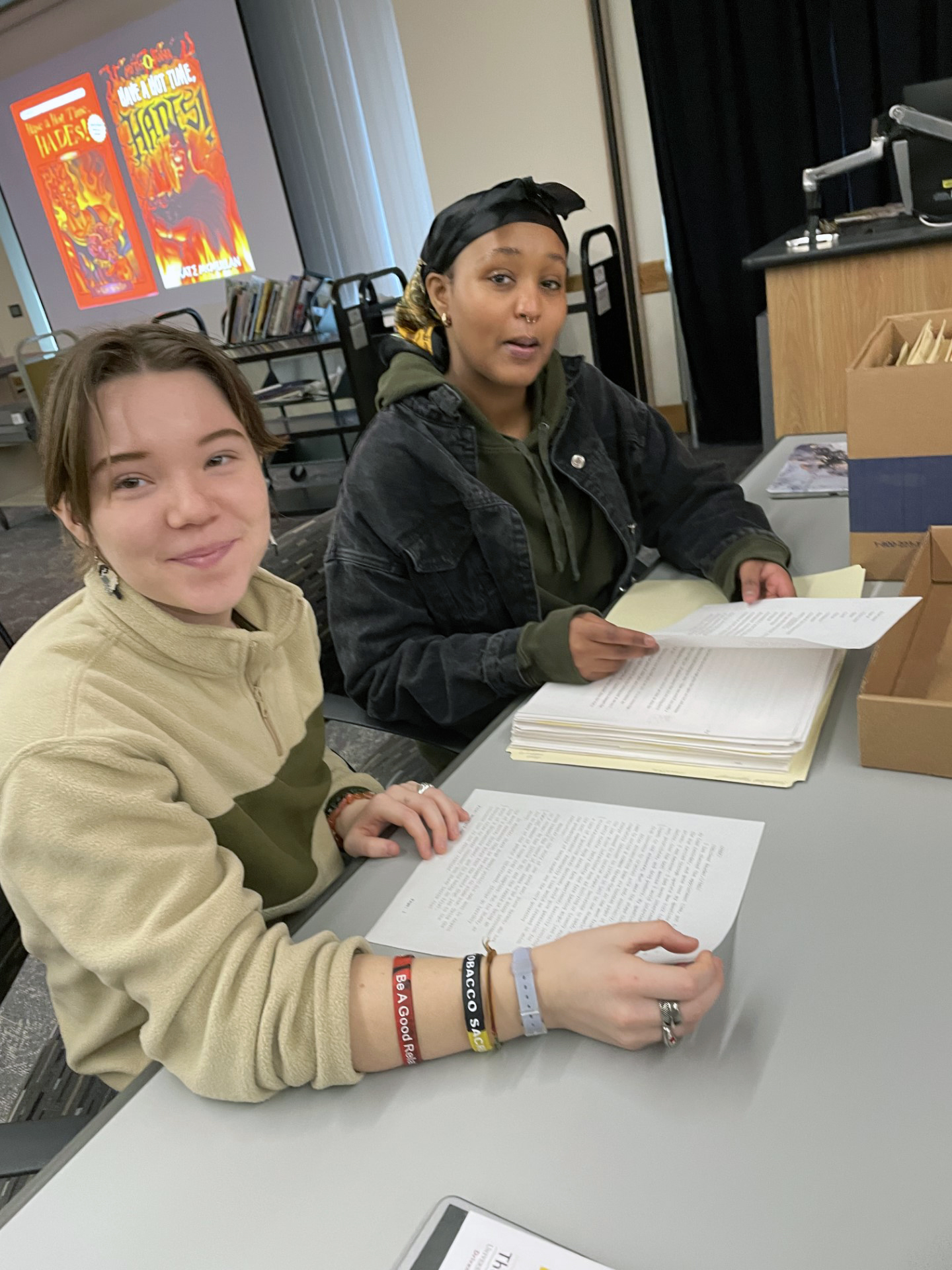 Two students sit at a table viewing typed manuscript materials