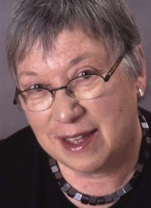 Headshot of children's author Robie Harris with short cropped hair and glasses wearing a necklace with square beads