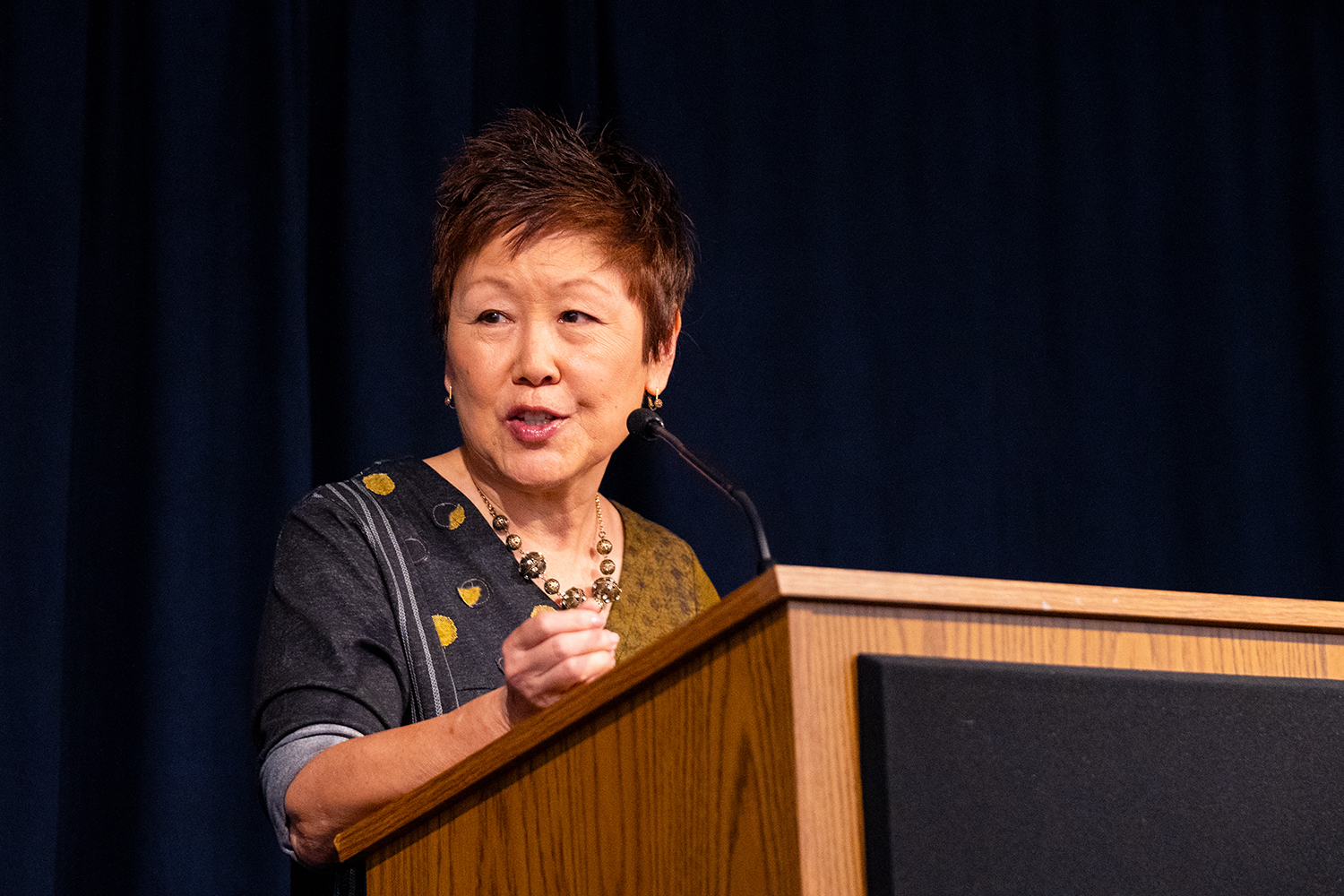 Lisa Yee stands at a podium mid-speech