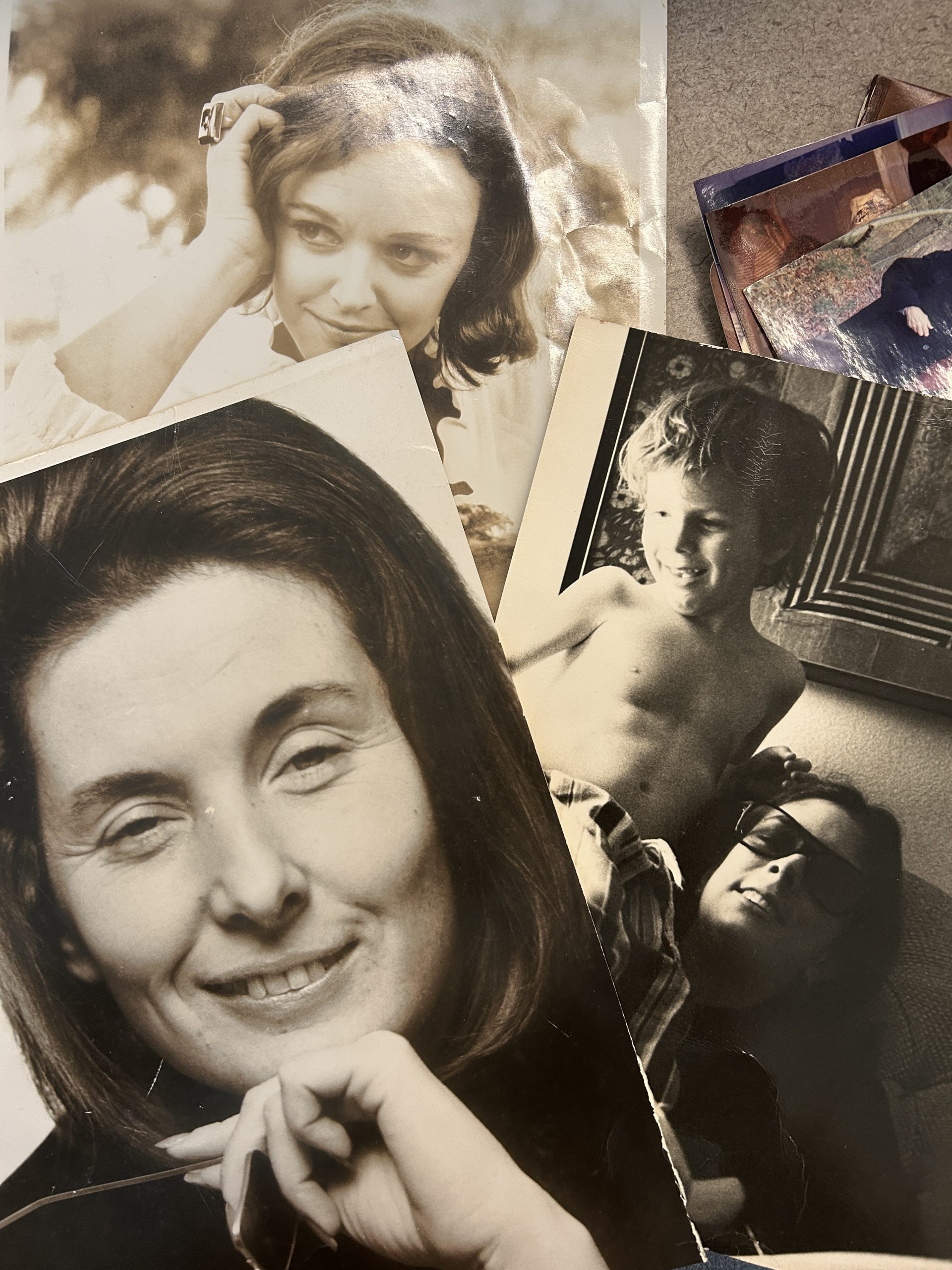 Three black and white photos laid on top of each other on a table featuring women with short hair smiling into the camera, and a small child standing next to a woman in sunglasses